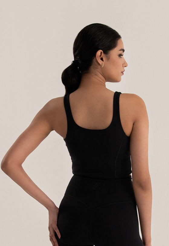 Woman wearing a black tank top and shorts on a plain background